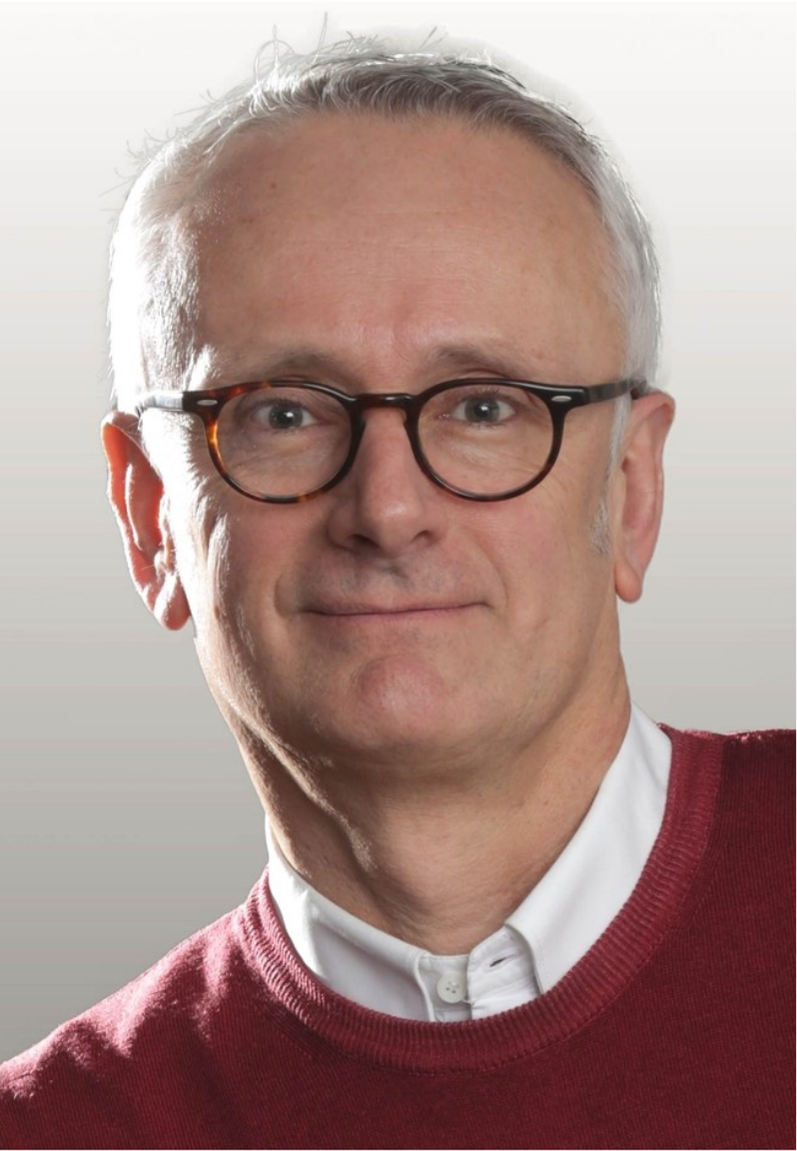 Portrait photograph of Prof François Chaumont. A man wearing a red jumper, with glasses and short grey hair smiling gently.