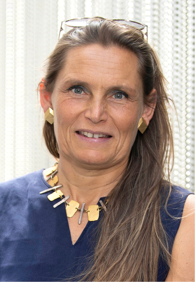 Portrait photograph of Prof Sandrine Etienne-Manneville. An elegantly dressed woman with long brown hair. She smiles broadly.