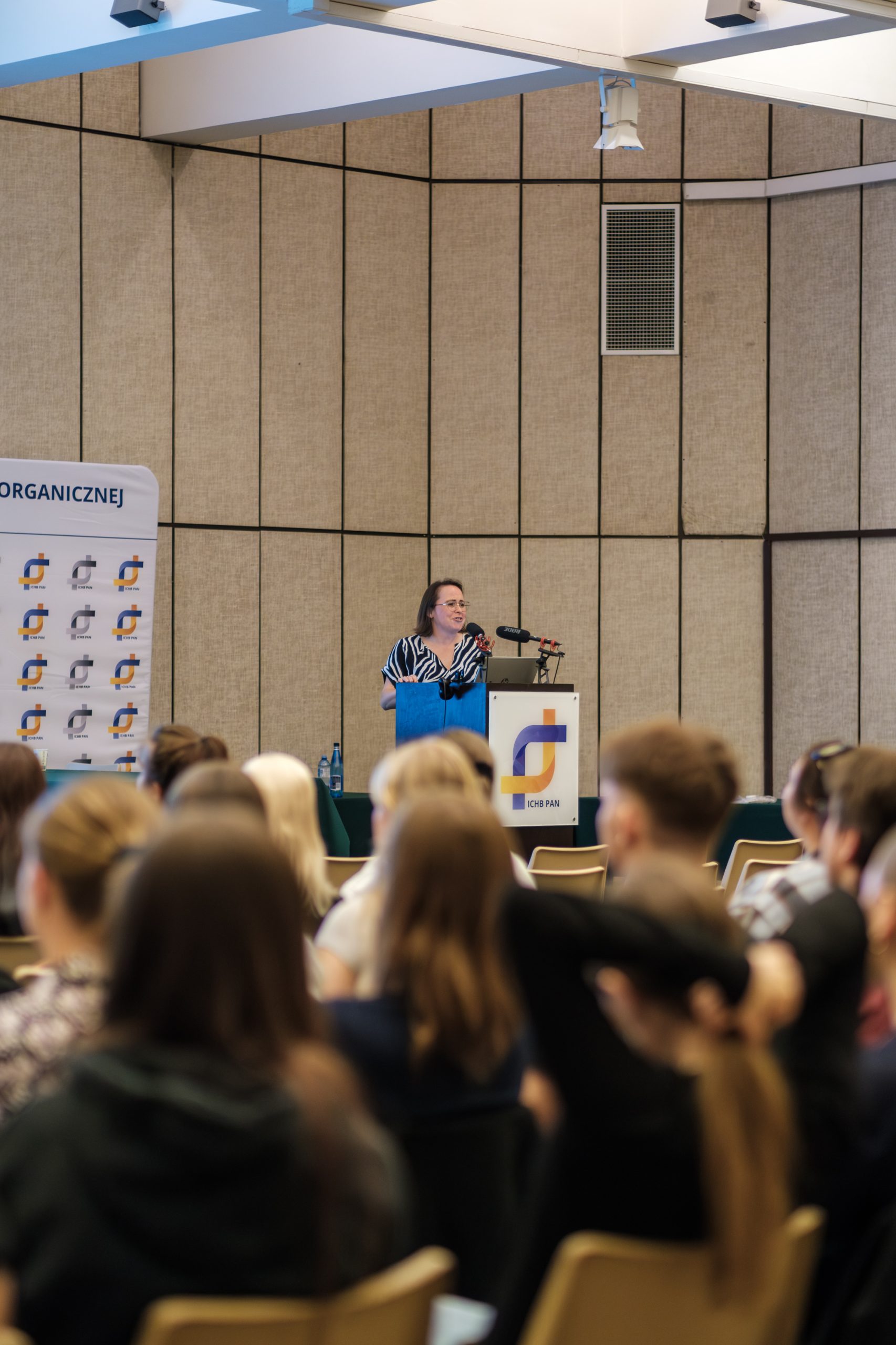 Kobieta prowadzi prezentację przed dużą publicznością w sali konferencyjnej