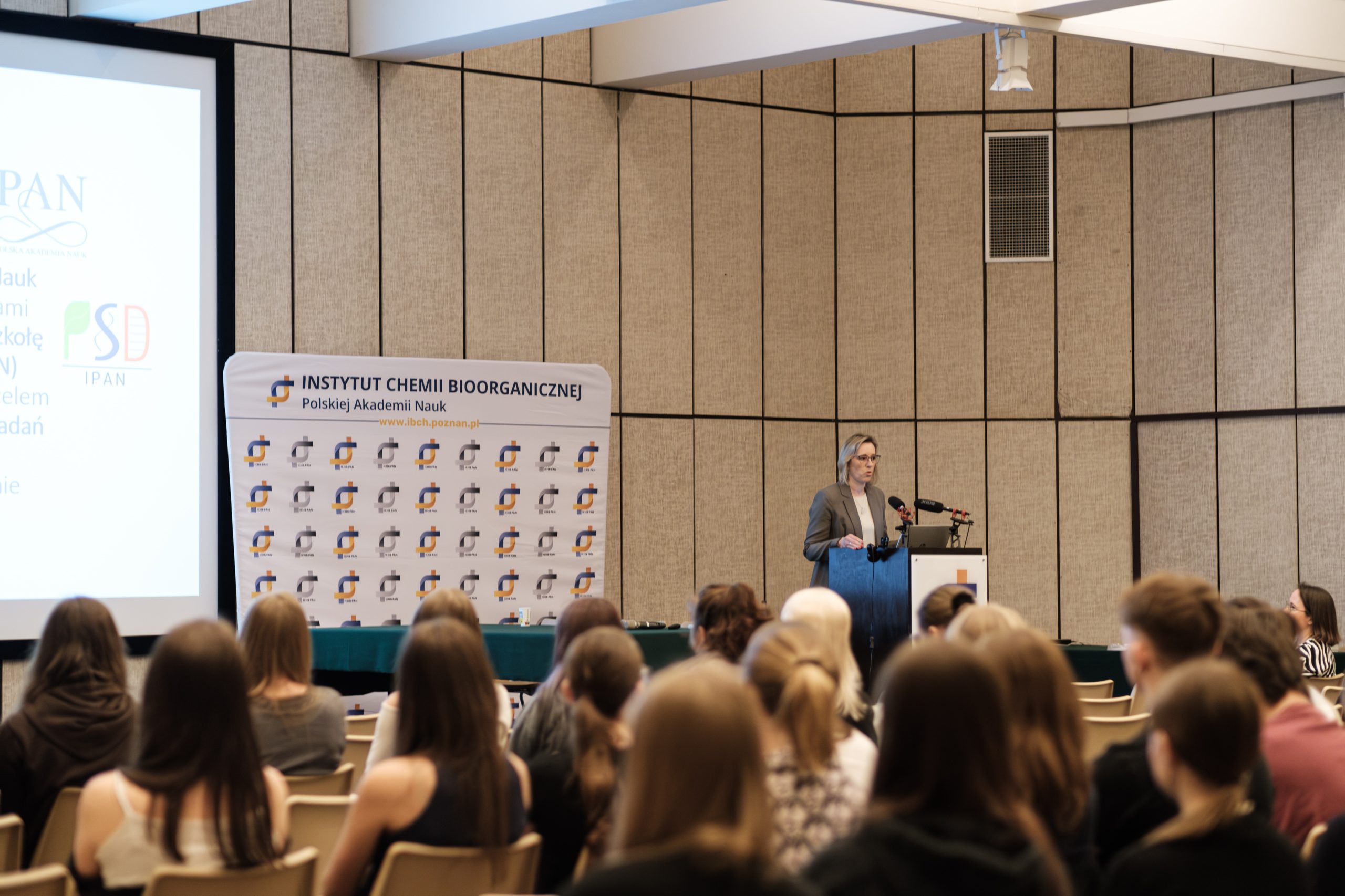 Kobieta prowadzi prezentację przed dużą publicznością w sali konferencyjnej