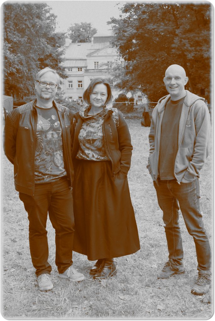 Sepia photo: one woman and two men; behind them, a meadow and a palace