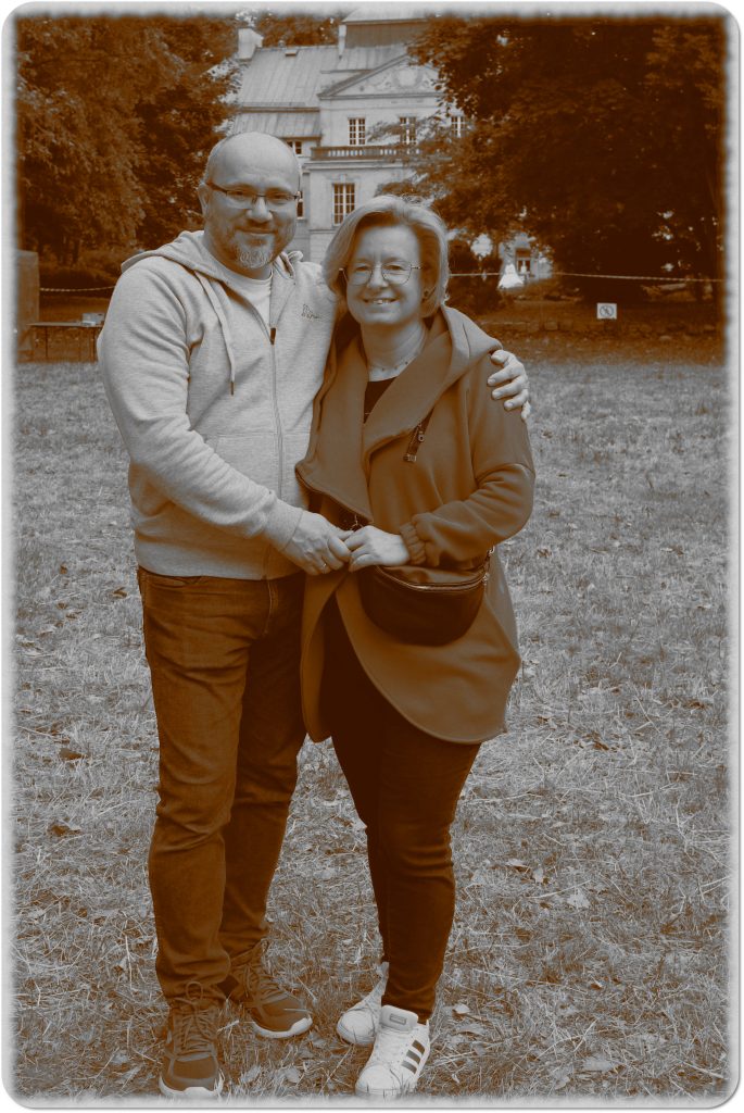 Sepia photo: a woman and a man holding hands; behind them, a meadow and a palace