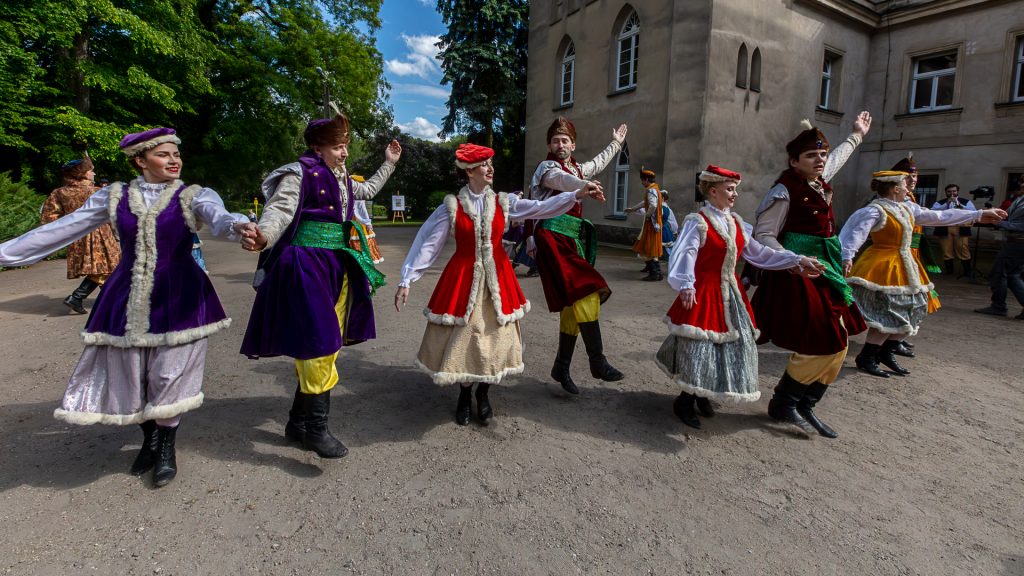 Four pairs dancing a folk dance in folk costumes