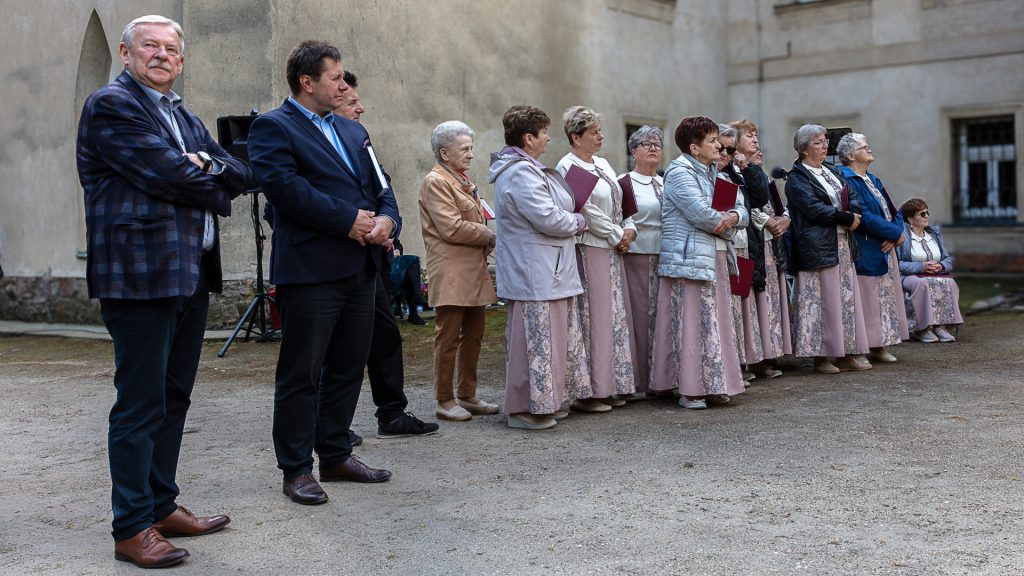 A group of women and men standing in front of the palace; the women are dressed alike