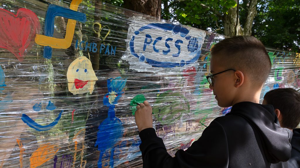chłopiec maluje farbami na folii umieszczonej między drzewami