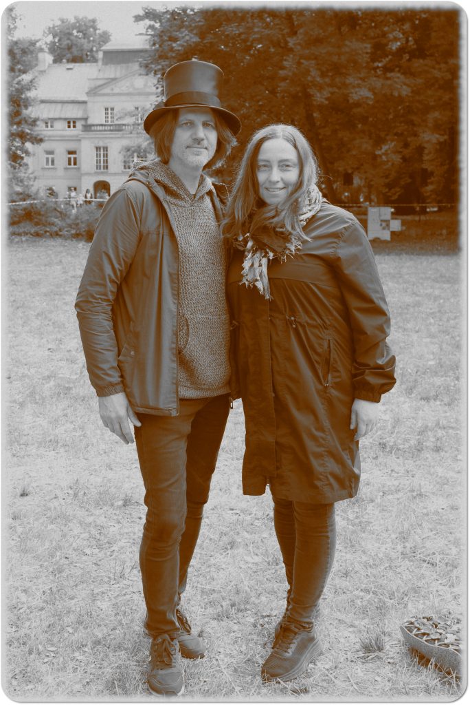Sepia photo: a woman and a man in a top hat; behind them, a meadow and a palace