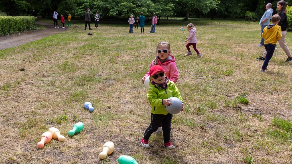 On the meadow, children stand holding bocce balls