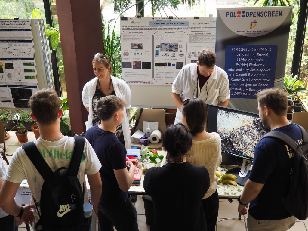A group of young people listening and watching the Medicinal Chemistry Laboratory stand with interest