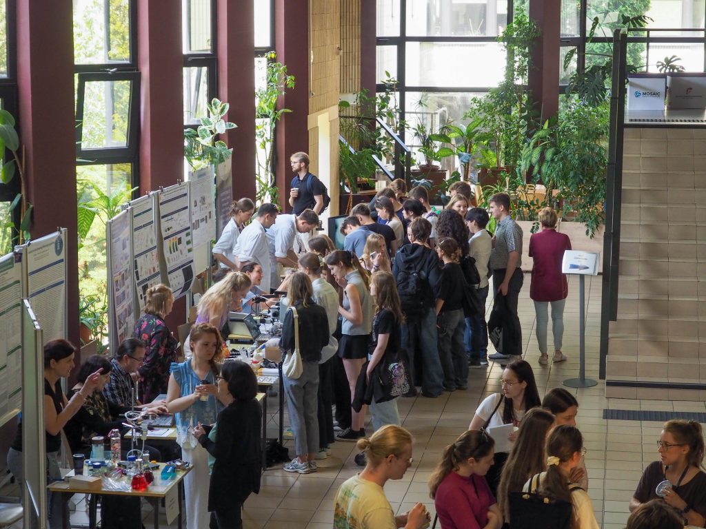 A crowd of young people in the lobby of the IBCH PAS, watching the stands of the plants and studios with curiosity