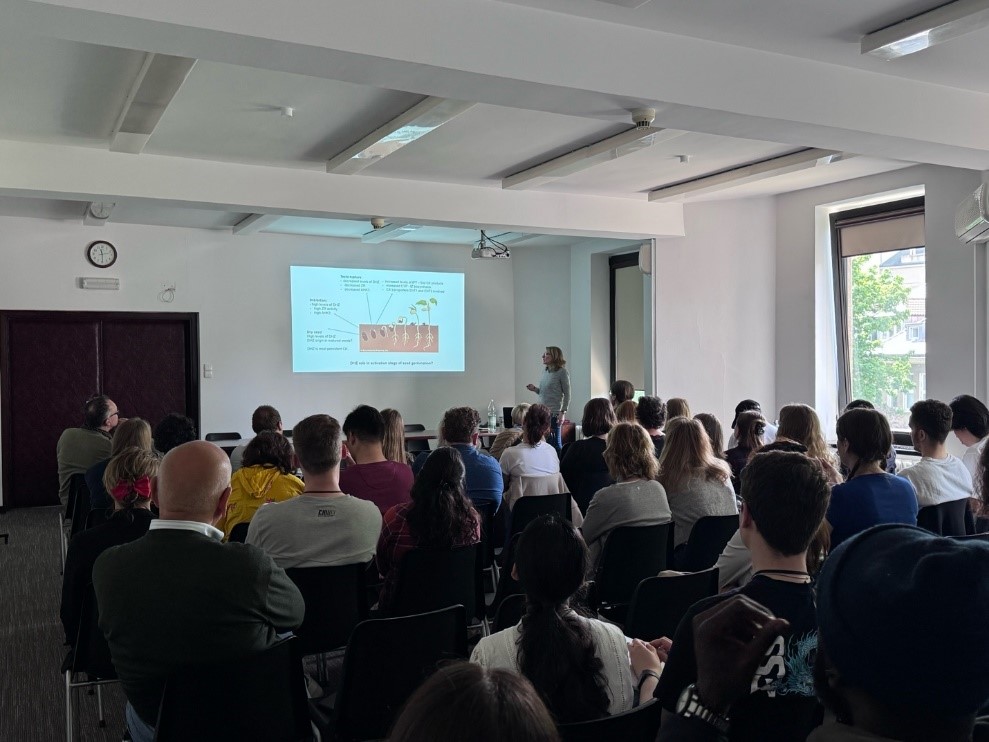 Dr. Klára Hoyerová is giving a lecture, with a crowd of interested listeners sitting in front of her.