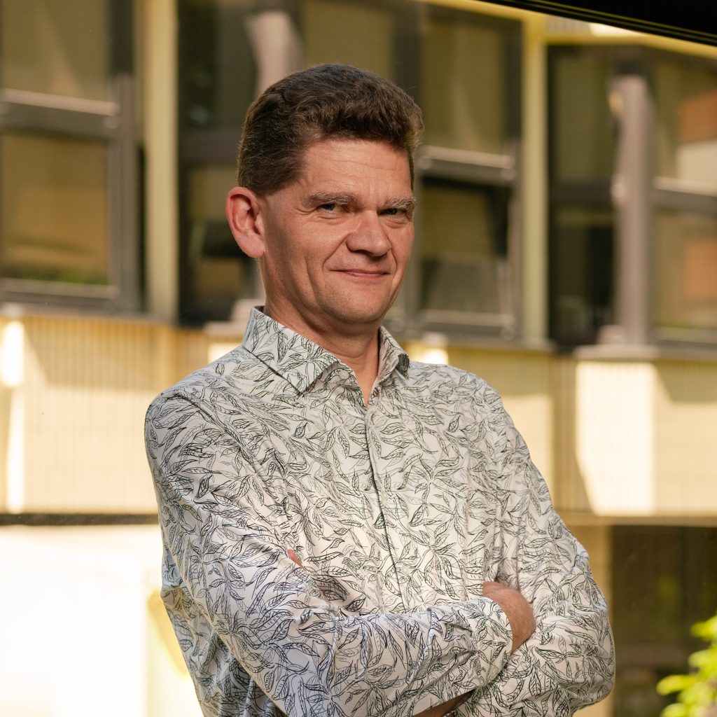 Photo of Prof. Paweł Bednarek, a portrait photo in front of the IBCH PAS building