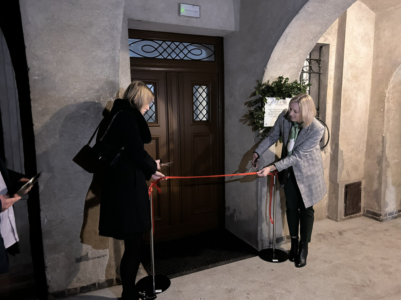 05.	Dwie kobiety przy drzwiach zewnętrznych Pałacu podczas uroczystego przecięcia wstęgi.