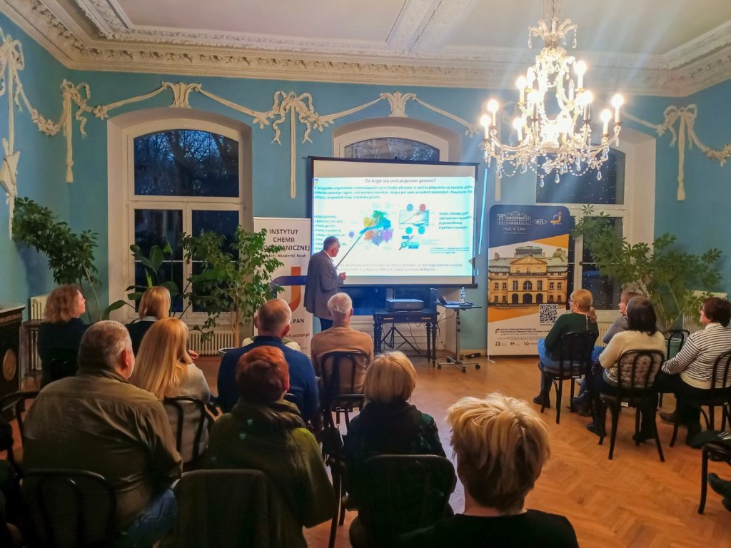 Prof. Marek Figlerowicz is giving a lecture in the Blue Hall of the Palace in Turew, while a group of listeners listens attentively