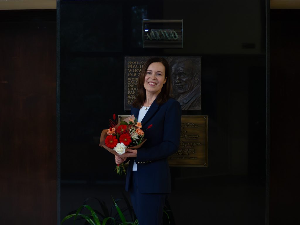 A portrait photograph of Katarzyna Klonowska next to the commemorative plaque of the Institute’s founder