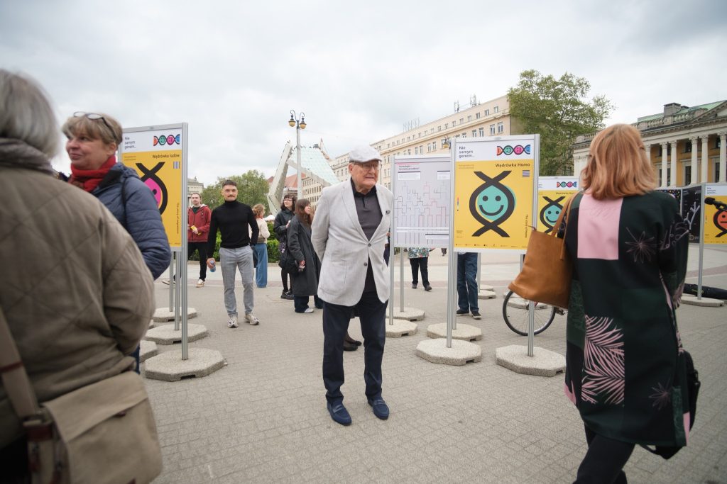 Zwiedzanie wystawy. Wiele osób ogląda prace. W centrum starszy mężczyzna oglądający wystawę