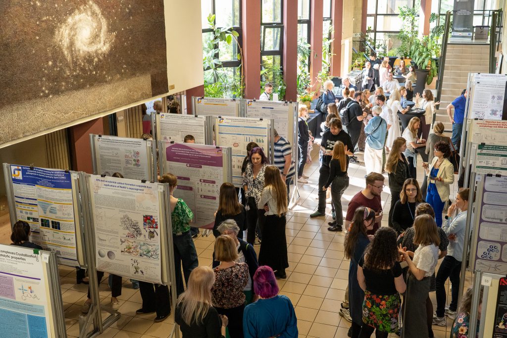Participants in the Institute's lobby. Some of them are viewing the posters, while others are talking and drinking coffee.