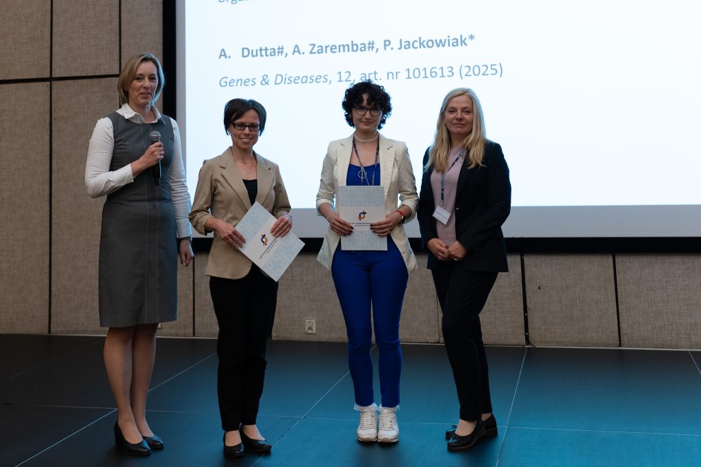 : Four women are standing on stage. Two of them are receiving an award.